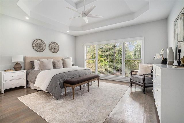 bedroom with a raised ceiling, dark wood finished floors, recessed lighting, and a ceiling fan
