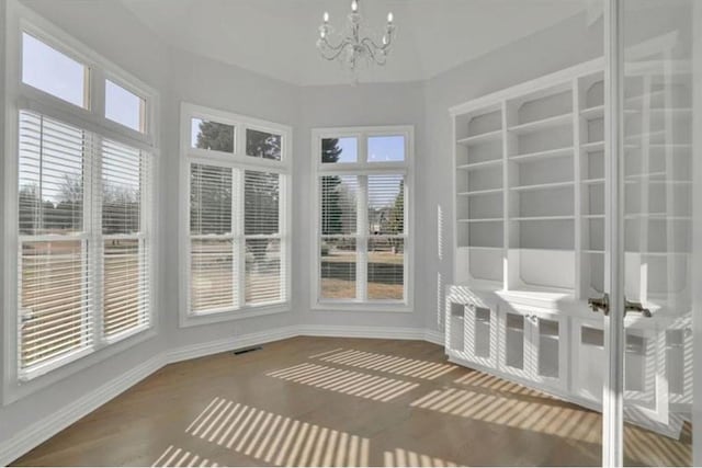 unfurnished sunroom featuring visible vents and an inviting chandelier