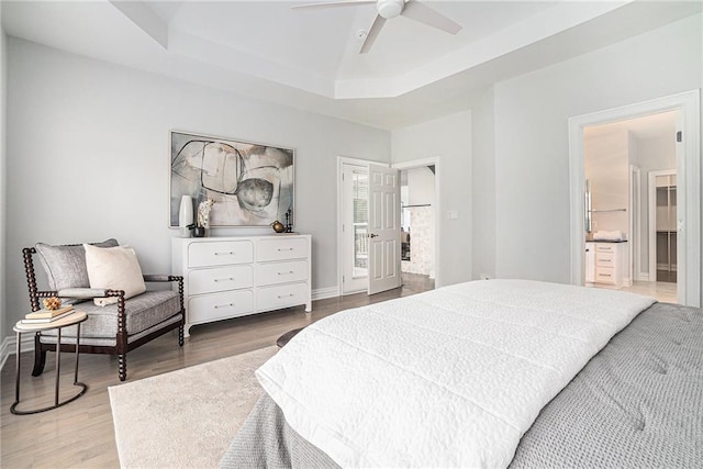 bedroom featuring a tray ceiling, wood finished floors, and a ceiling fan