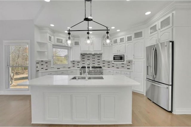 kitchen with appliances with stainless steel finishes, white cabinetry, light countertops, and a sink