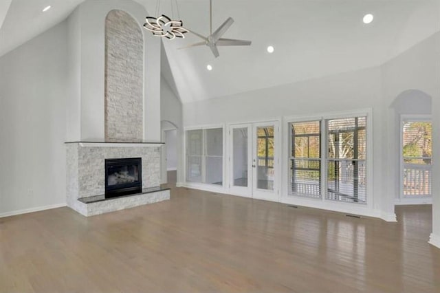 unfurnished living room with high vaulted ceiling, wood finished floors, a fireplace, a ceiling fan, and baseboards