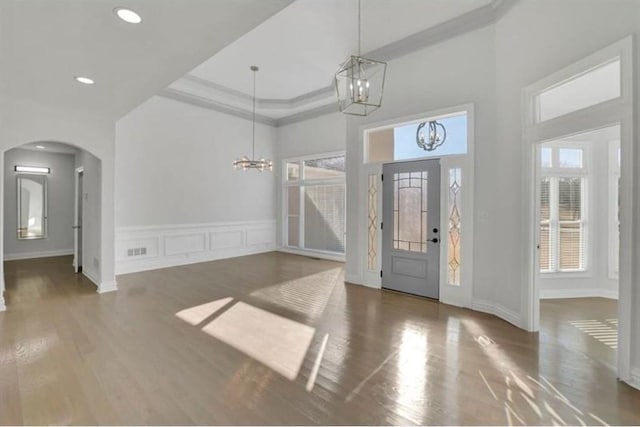 foyer entrance featuring a chandelier, arched walkways, a towering ceiling, wood finished floors, and recessed lighting