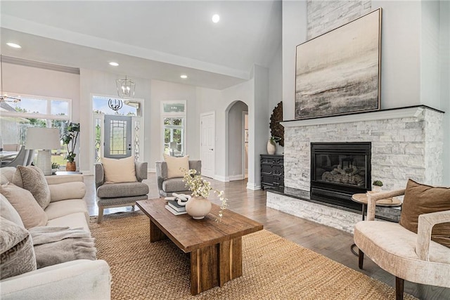 living room featuring recessed lighting, baseboards, wood finished floors, arched walkways, and a fireplace
