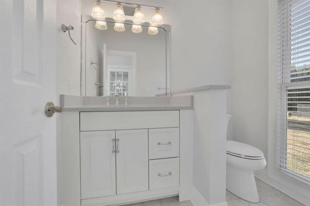bathroom featuring toilet, vanity, and marble look tile flooring