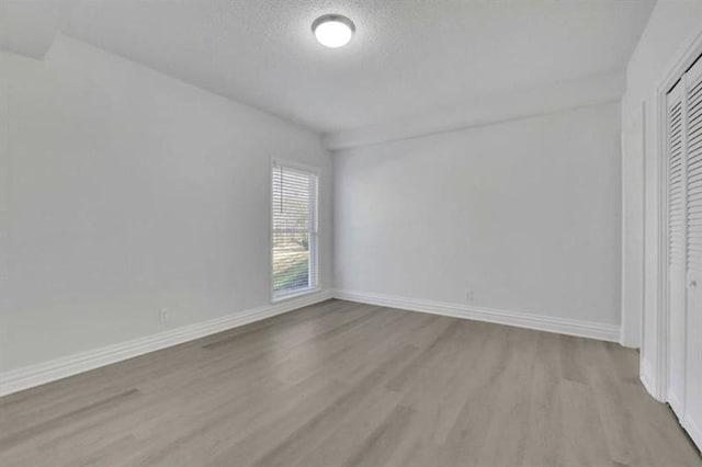 interior space featuring wood finished floors, baseboards, a closet, and a textured ceiling