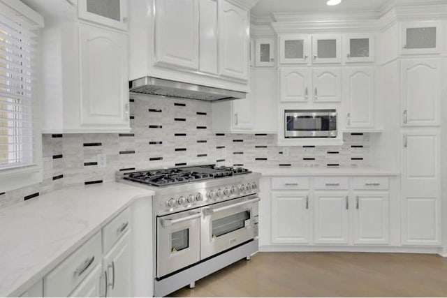 kitchen with stainless steel appliances, white cabinetry, glass insert cabinets, backsplash, and light wood-style floors