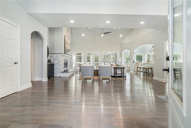 living area with arched walkways, a ceiling fan, wood finished floors, a fireplace, and recessed lighting