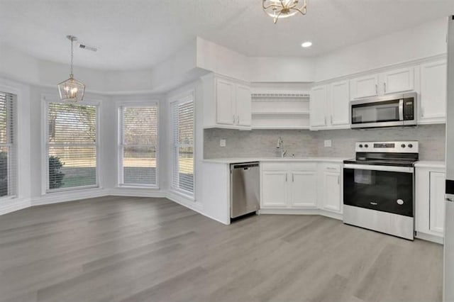 kitchen with light wood-type flooring, open shelves, tasteful backsplash, stainless steel appliances, and light countertops