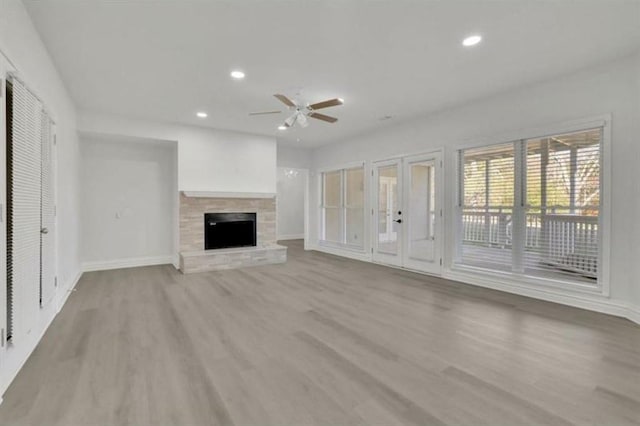 unfurnished living room with recessed lighting, a fireplace with raised hearth, light wood-style floors, and baseboards