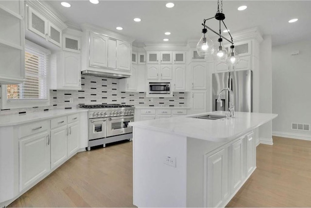 kitchen with visible vents, a sink, stainless steel appliances, white cabinets, and light wood-type flooring