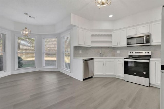 kitchen featuring stainless steel appliances, a chandelier, light wood finished floors, light countertops, and recessed lighting