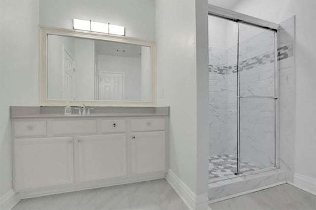 bathroom with baseboards, a marble finish shower, marble look tile flooring, and vanity