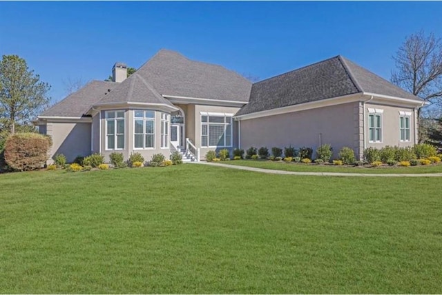 view of front of property with stucco siding, a chimney, and a front lawn