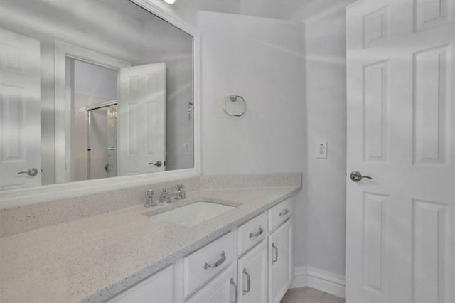 full bath with vanity, a shower with shower door, tile patterned flooring, and baseboards
