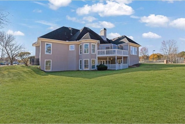 rear view of property featuring a balcony, a chimney, and a yard