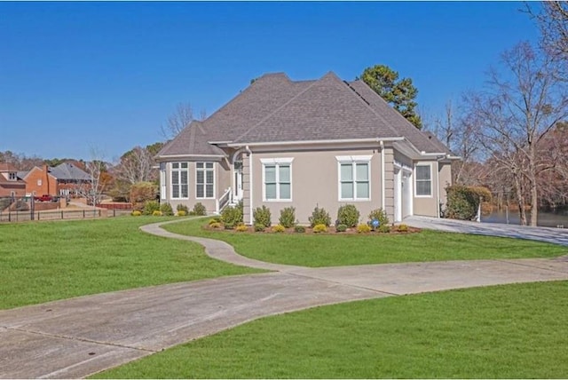 view of front facade featuring a front yard, fence, driveway, stucco siding, and a garage