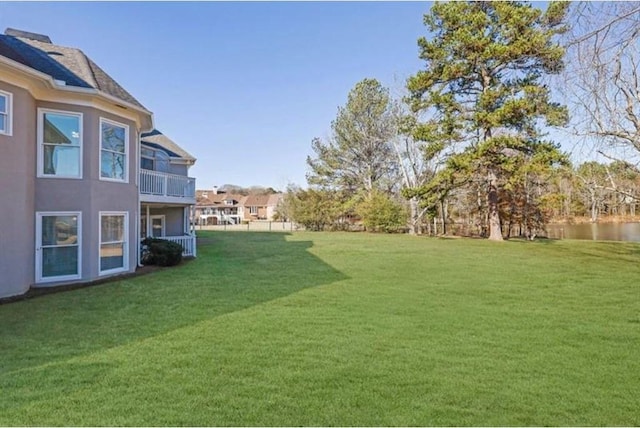 view of green lawn with a balcony