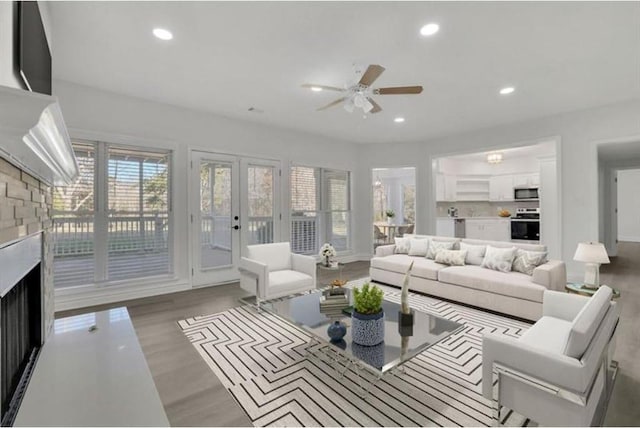 living room featuring ceiling fan, recessed lighting, a fireplace, french doors, and wood finished floors