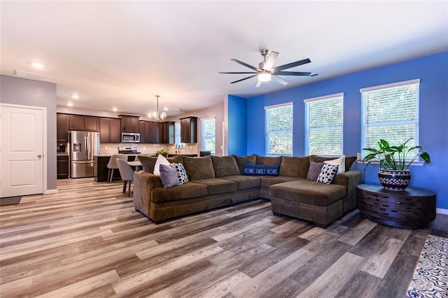 living room featuring light wood-type flooring and ceiling fan with notable chandelier