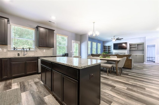 kitchen featuring hardwood / wood-style flooring, ceiling fan with notable chandelier, hanging light fixtures, and decorative backsplash