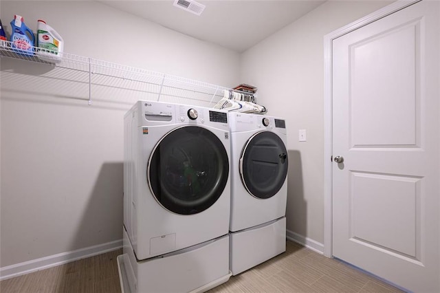 laundry area with light wood-type flooring and washing machine and clothes dryer