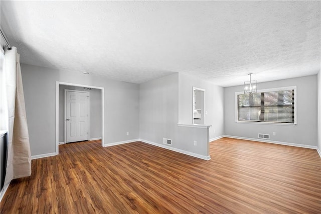 4347 Pleasant Ridge Rd, Decatur, GA 30034 - unfurnished living room with a textured ceiling, baseboards, visible vents, a chandelier, and wood finished floors