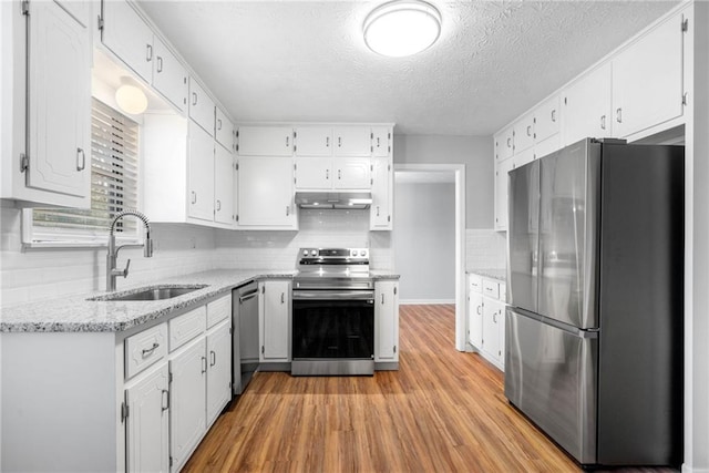 4347 Pleasant Ridge Rd, Decatur, GA 30034 - kitchen with white cabinets, a sink, light wood-type flooring, under cabinet range hood, and appliances with stainless steel finishes