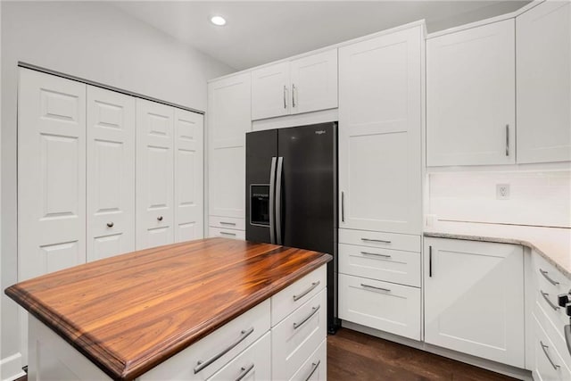 kitchen featuring white cabinets, wooden counters, black refrigerator with ice dispenser, dark wood-type flooring, and decorative backsplash