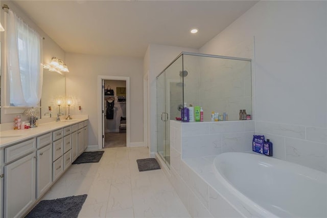 bathroom with a walk in closet, marble finish floor, a garden tub, a stall shower, and a sink