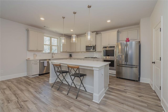 325 Caledonia Ct, Peachtree City, GA 30269 - kitchen with appliances with stainless steel finishes, a center island, light countertops, light wood-type flooring, and a kitchen bar