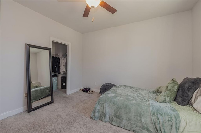 bedroom featuring a closet, a spacious closet, light carpet, ceiling fan, and baseboards