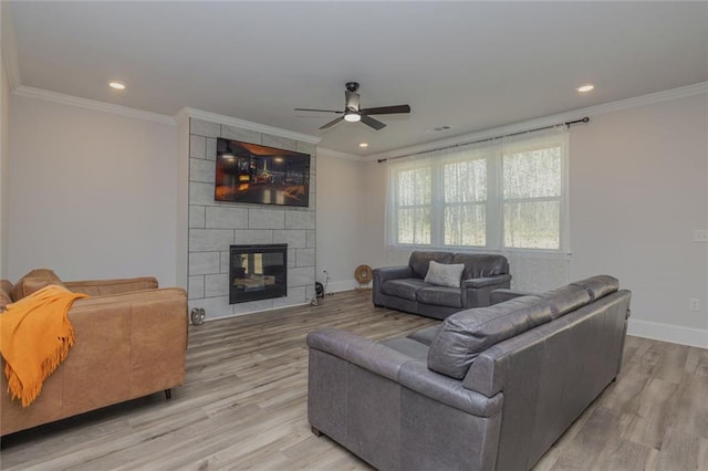 living room featuring baseboards, a tile fireplace, light wood-style flooring, and crown molding