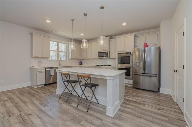 kitchen featuring light wood-style floors, stainless steel appliances, light countertops, and a center island