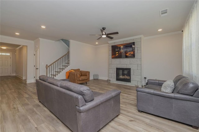 living area with visible vents, a fireplace, stairway, and light wood finished floors