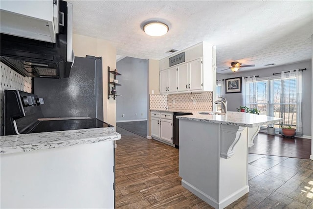 kitchen with white cabinetry, a breakfast bar area, range, and a textured ceiling