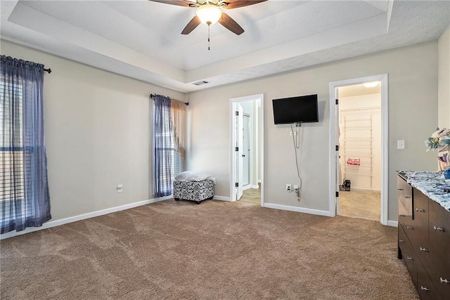 unfurnished bedroom with carpet floors, a raised ceiling, and ceiling fan