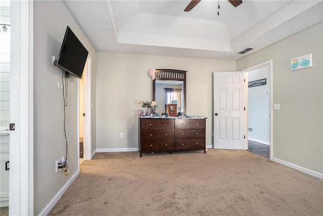 unfurnished bedroom featuring a tray ceiling, light colored carpet, and ceiling fan