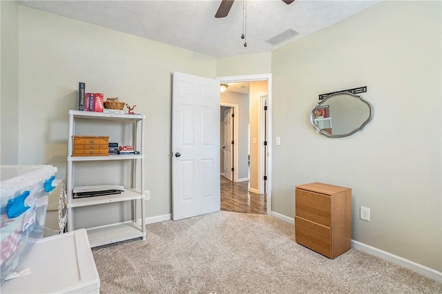 carpeted bedroom with ceiling fan and a textured ceiling