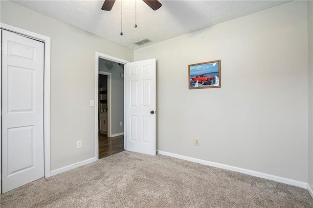 unfurnished bedroom featuring ceiling fan, carpet flooring, a closet, and a textured ceiling