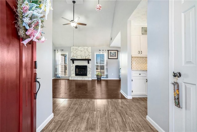 unfurnished living room with a fireplace, wood-type flooring, ceiling fan, and vaulted ceiling