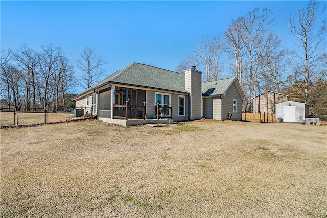 back of house featuring a storage shed, a sunroom, and a lawn