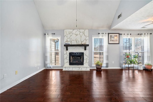 unfurnished living room with a stone fireplace, dark wood-type flooring, and lofted ceiling