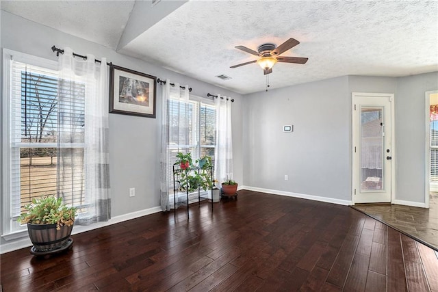 interior space featuring ceiling fan, dark wood-type flooring, and a textured ceiling