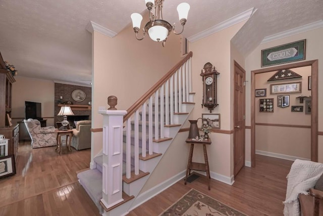 3743 Johnston Rd, Winston, GA 30187 - stairs with a chandelier, wood finished floors, crown molding, a textured ceiling, and a fireplace