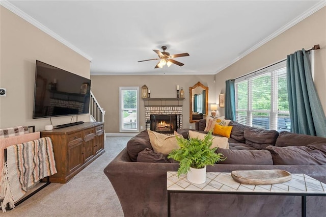 carpeted living room featuring crown molding, a brick fireplace, and a ceiling fan