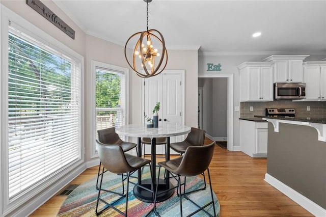 dining area featuring an inviting chandelier, light wood-style floors, baseboards, and ornamental molding