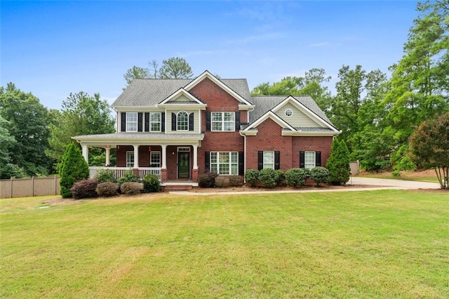 view of front of home featuring brick siding, a porch, a front lawn, and fence