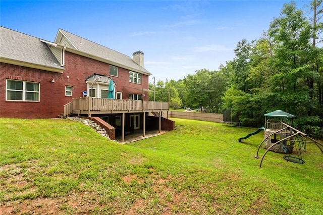 view of yard with a deck, a playground, a trampoline, and fence