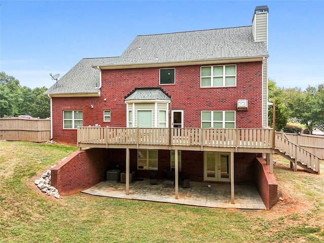 back of property with brick siding, french doors, a yard, and fence