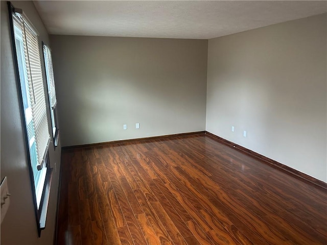 empty room featuring dark wood-style flooring and baseboards